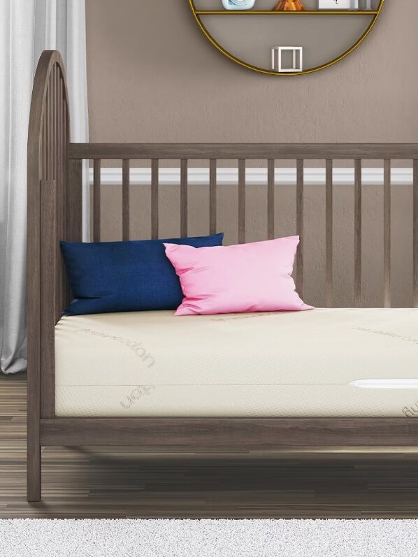 A Saatva crib mattress with two pillows.