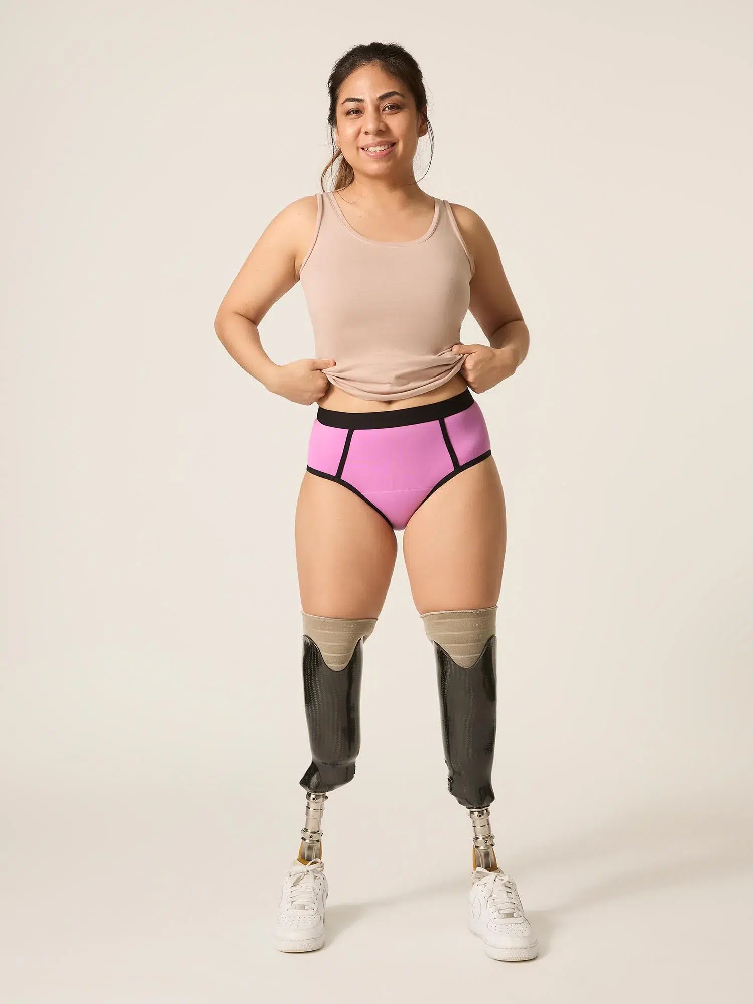 A woman with prosthetic legs lifts her tank top to show off her ModiBodi period underwear. 